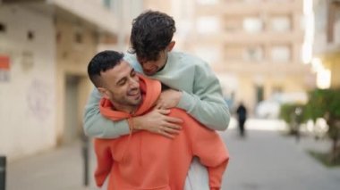 Young hispanic couple smiling confident hugging each other at street