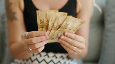 Young woman counting south africa 20 rand banknotes at home