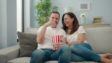 Kadın ve erkek, evdeki kanepede film seyrediyor.