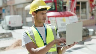 Young hispanic man architect using laptop at park