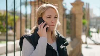 Genç sarışın kadın gülümsüyor. Kendine güveni tam. Akıllı telefondan konuşuyor.