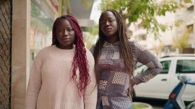 Two african american women smiling confident standing with arms crossed gesture at street