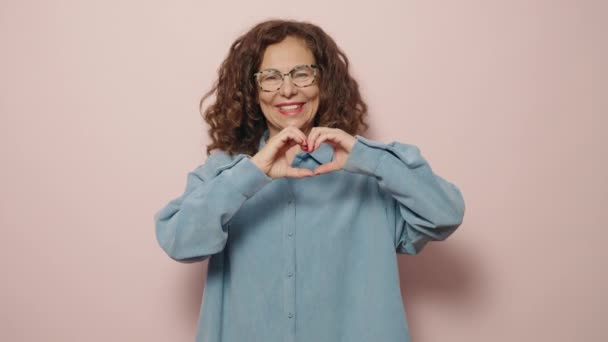 Kobieta Średnim Wieku Uśmiechnięta Pewnie Robi Symbol Serca Rękami Różowym — Wideo stockowe