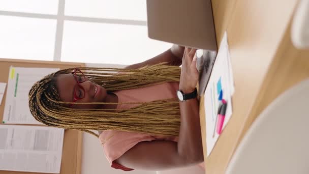 アフリカ系アメリカ人女性のビジネス労働者がオフィスでドキュメント垂直ビデオでノートパソコンの書き込みを使用 — ストック動画