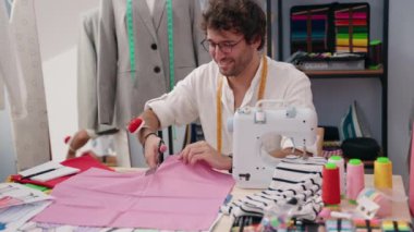 Genç İspanyol terzi gülümsüyor. Kıyafet fabrikasında kumaş kesiyor.