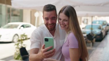 Man and woman couple smiling confident using smartphone at street