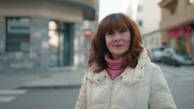 Middle age redhead woman smiling confident standing at street