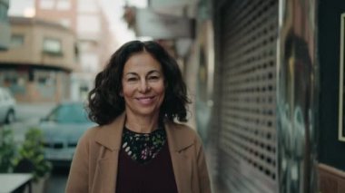 Middle age hispanic woman smiling confident walking at street