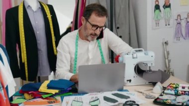 Terzide bilgisayarla konuşan orta yaşlı bir terzi.