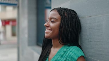 Afro-Amerikalı kadın gülümsüyor. Kendinden emin bir şekilde caddeye bakıyor.