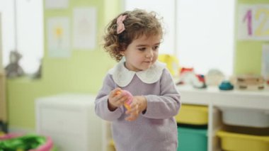 Adorable hispanic girl standing on back view at kindergarten
