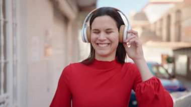 Young woman smiling confident listening to music at street
