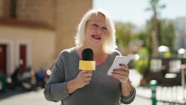 Middle Age Blonde Woman Reporter Working Using Microphone Reading Notebook — Stockvideo