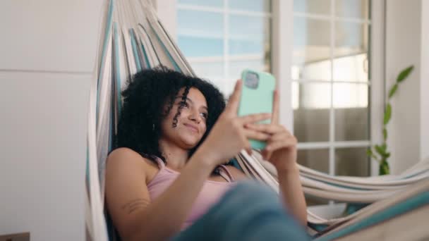 Young Hispanic Woman Using Smartphone Lying Hammock Home Terrace — Stockvideo