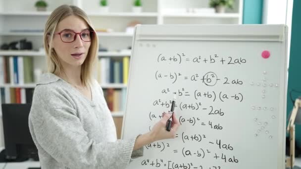 图书馆大学的年轻金发女子在磁板上教数学 — 图库视频影像