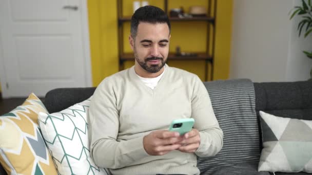 Ung Latinamerikan Man Med Smartphone Gör Gest Hemma — Stockvideo