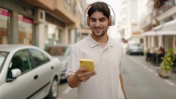 Jeune Homme Hispanique Souriant Confiant Écoutant Musique Marcher Dans Rue — Video