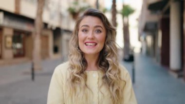 Genç sarışın kadın gülümsüyor. Kendinden emin konuşuyor.