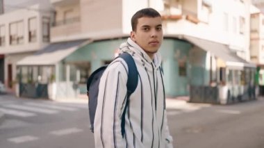 Young man student smiling confident standing with arms crossed gesture at street