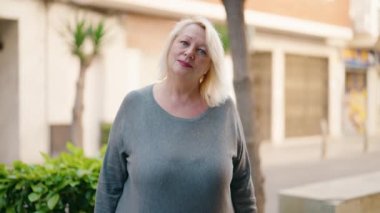 Middle age blonde woman smiling confident shake hand at street