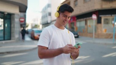 Genç İspanyol adam, kendine güvenen, sokakta akıllı telefon kullanan, müzik dinleyen.