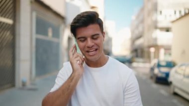 Genç İspanyol adam gülümsüyor. Kendine güveniyor. Sokakta akıllı telefondan konuşuyor.