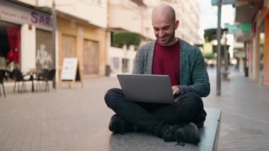Young bald man smiling confident using laptop at street