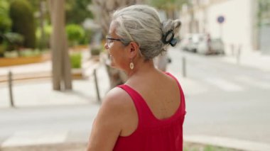 Middle age grey-haired woman standing with arms crossed gesture at street