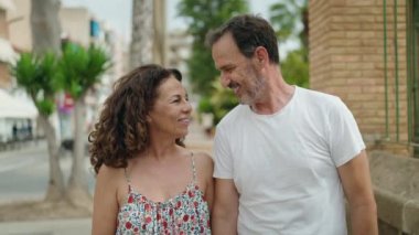 Man and woman couple standing together kissing at street