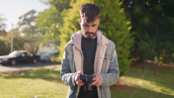 Young Hispanic Man Standing Serious Expression Using Camera Park — Vídeo de Stock
