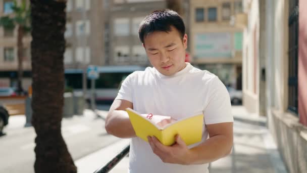 Young Chinese Man Smiling Confident Reading Book Street — ストック動画