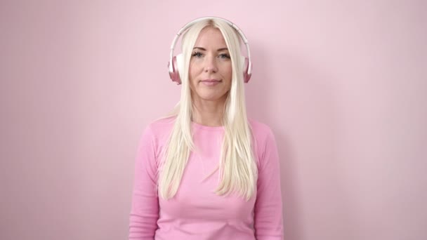 Giovane Donna Bionda Sorridente Fiducioso Ascoltare Musica Sfondo Rosa Isolato — Video Stock