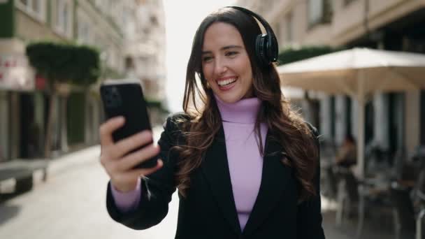 年轻的惊慌失措的女人带着自信的笑容在街上听音乐 — 图库视频影像