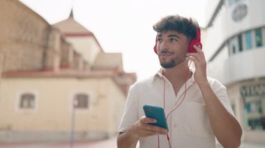 Young arab man listening to music walking at street