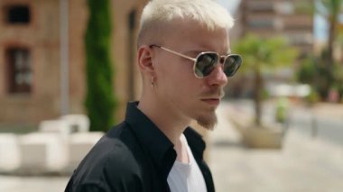 Sokakta ciddi bir ifadeyle duran beyaz bir genç.