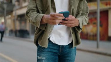 Sokakta akıllı telefon kullanan, kendine güvenen genç bir İspanyol.