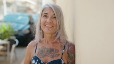 Middle age grey-haired woman smiling confident looking to the side at street