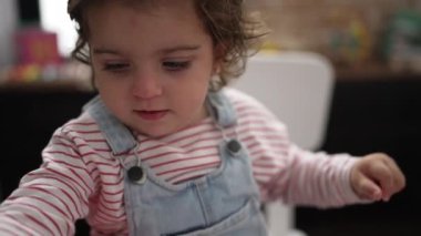 Anaokulunda masaya oturmuş kağıda resim çizen sevimli İspanyol kız öğrenci.