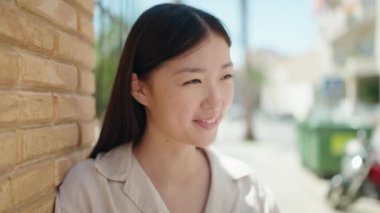 Çinli kadın gülümseyerek caddenin kenarına bakıyor.