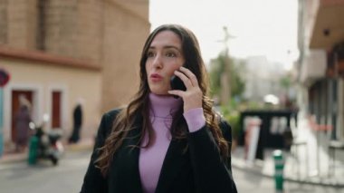 Genç İspanyol kadın gülümsüyor. Kendine güveniyor. Akıllı telefondan konuşuyor.
