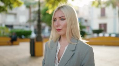 Young blonde woman executive smiling confident standing at park