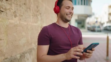 Young man smiling confident listening to music and dancing at street