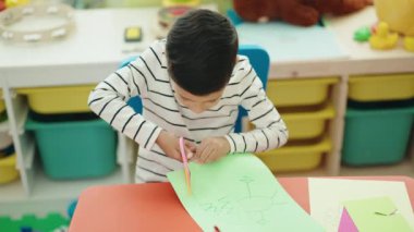 Anaokulunda kağıt kesen sevimli İspanyol çocuk.