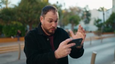Young plus size man playing video game at park