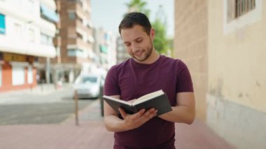 Genç adam gülümsüyor. Kendine güveniyor. Sokakta akıllı telefondan konuşuyor.