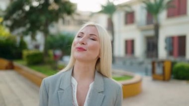 Young blonde woman executive smiling confident walking at park