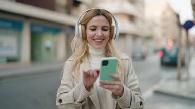 Sokakta müzik dinleyen kendine güvenen genç sarışın kadın.