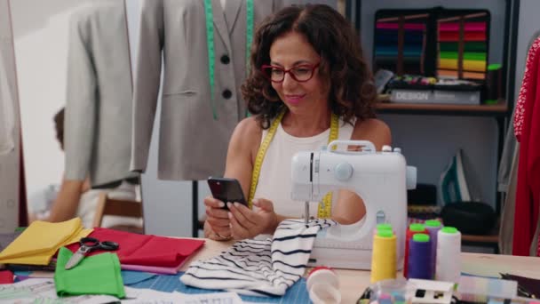 中年妇女裁缝笑着自信地使用智能手机在服装厂 — 图库视频影像