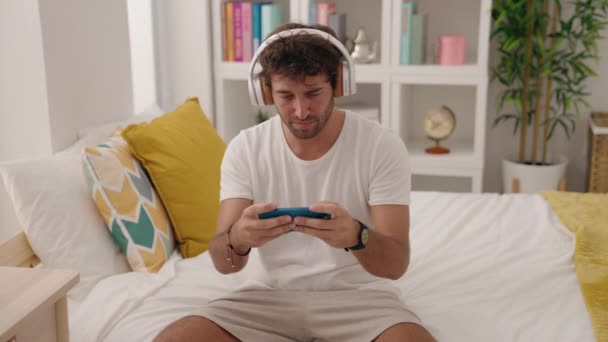 Young Hispanic Man Playing Video Game Sitting Bed Bedroom — Vídeo de Stock