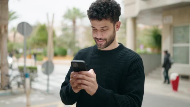 年轻的阿拉伯男子在街上用智能手机充满自信地微笑 — 图库视频影像